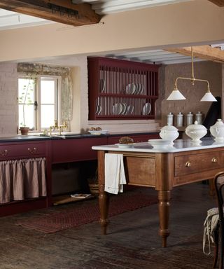 A white and burgundy kitchen with a wood island