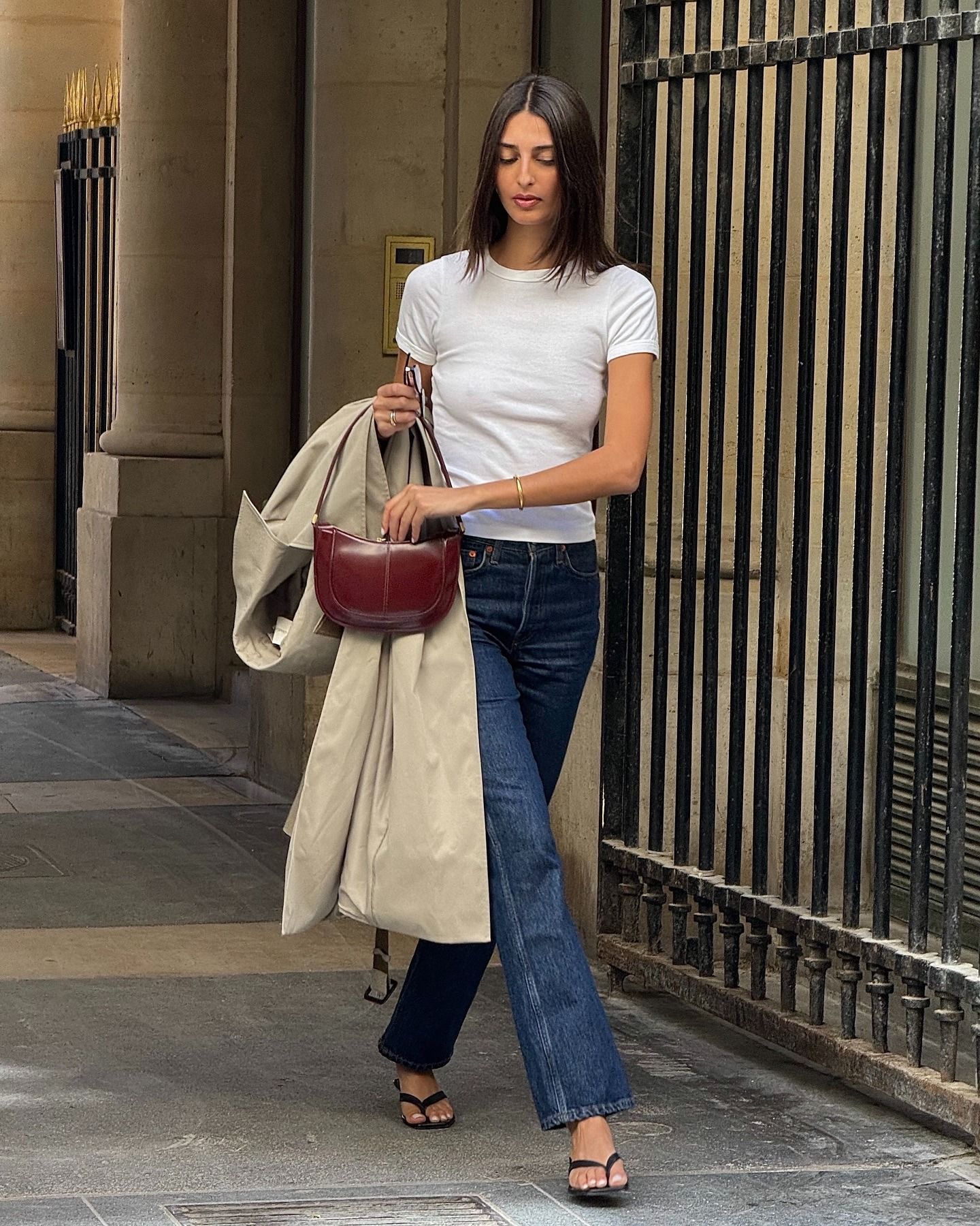 @salome.mory wearing a white T-shirt and jeans outfit with thong kitten heels, trench coat, and bag