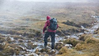 A hiker crosses a moor in windy winter weather