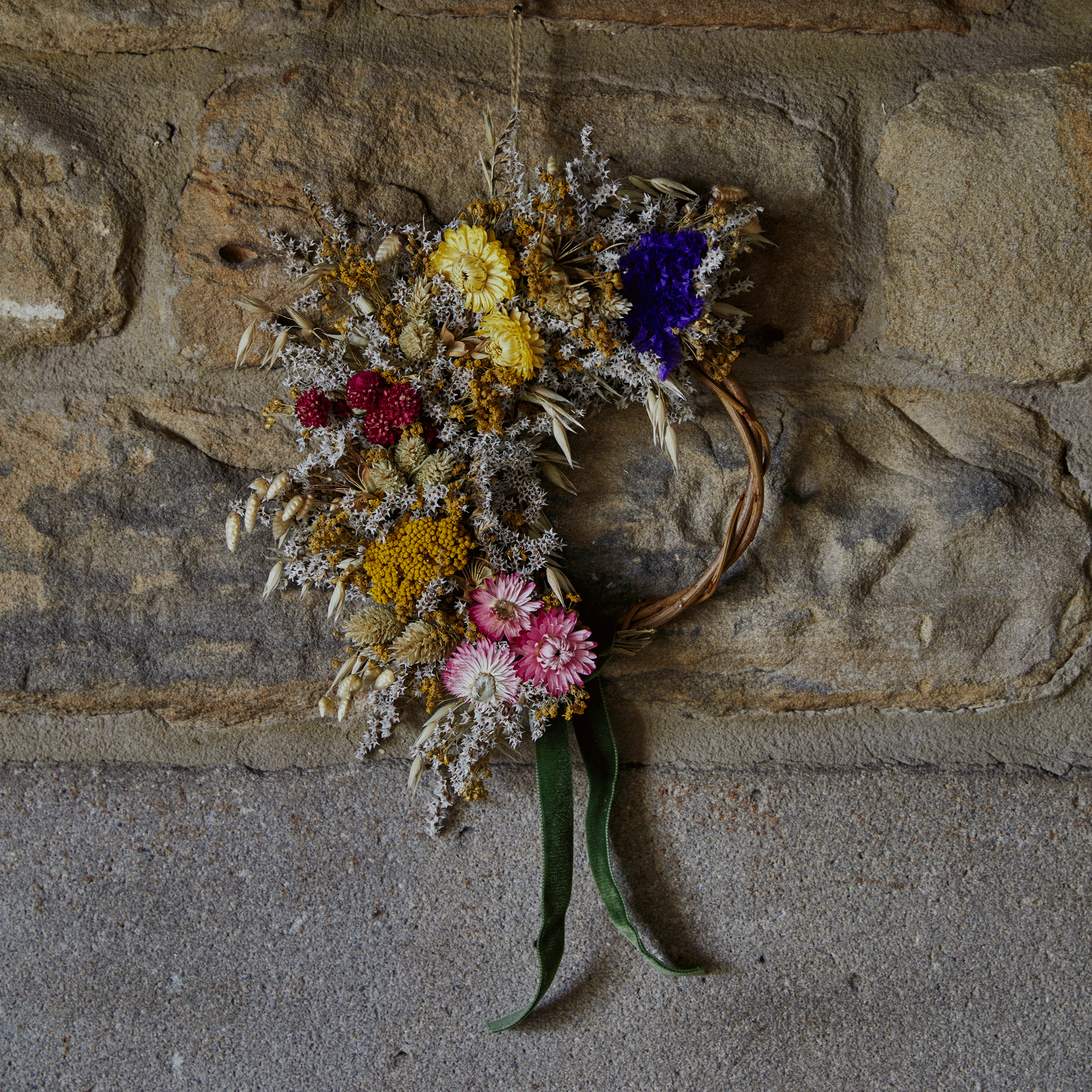 an exposed brick wall with a dried flower wreath hanging