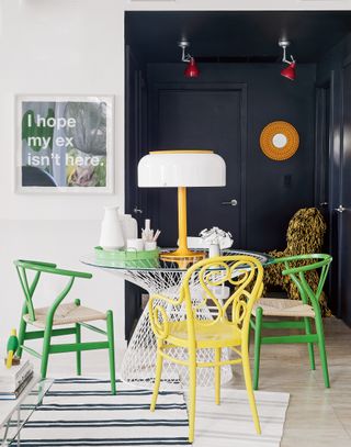 Black and white dining room with brightly colored chairs