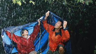 A father and son sheltering under a tarp
