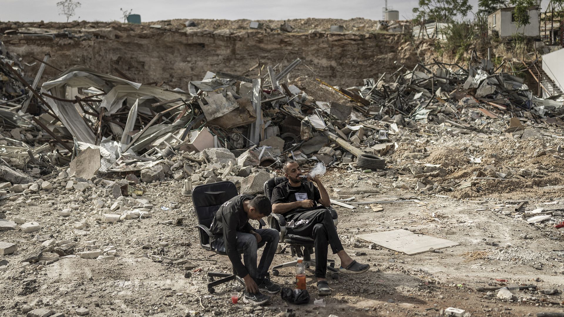 
                                Two Palestinian men relax amongst the ruins of businesses that were demolished by Israeli forces in the Israeli-occupied West Bank town of al-Eizariya 
                            