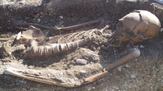 photo of a largely intact human skeleton partially buried at a site