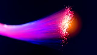 An image of an open fibre cable displaying the fibres in a pink light