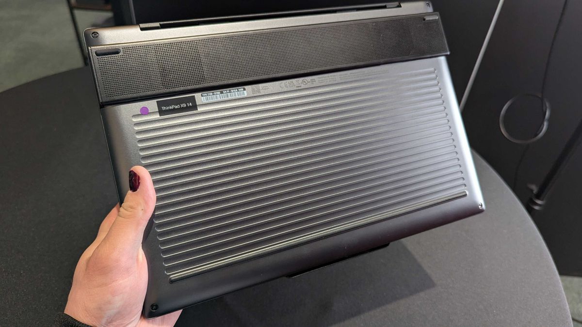 The Lenovo ThinkPad X9 Aura Edition held in the hand, showing its corrugated bottom and "Engine Hub."