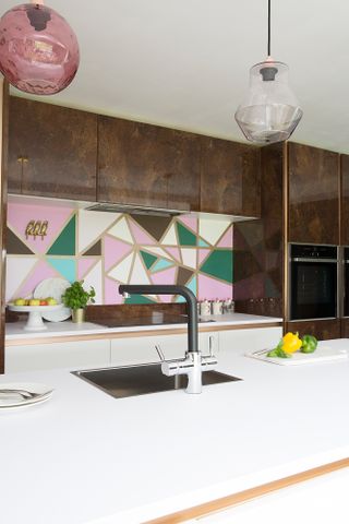 Kitchen with geometric painted splashback in pink, green, brown and white with gold border