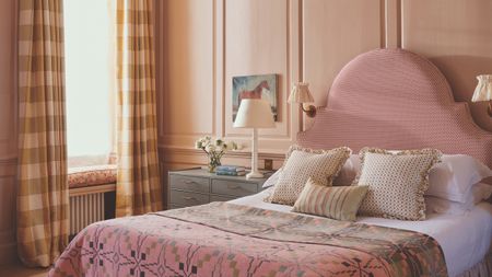 A blush bedroom with a pink statement headboard and plush linens 