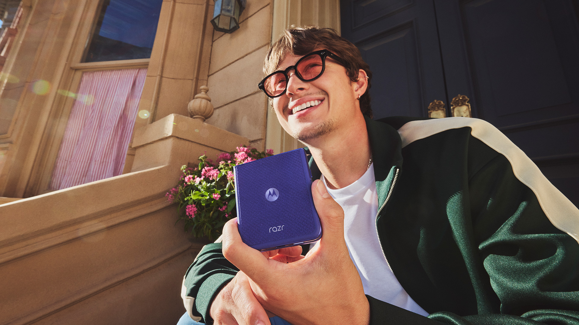 Man sitting on stoop and holding up the Motorola 70 Ultra