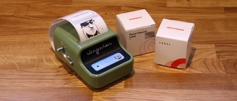 Niimbot B21 review; a small green label printer on a wooden table with rolls of printing paper