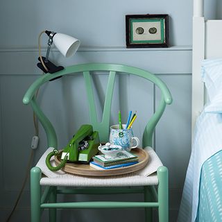 bedroom with light blue wall and pale green wishbone chair