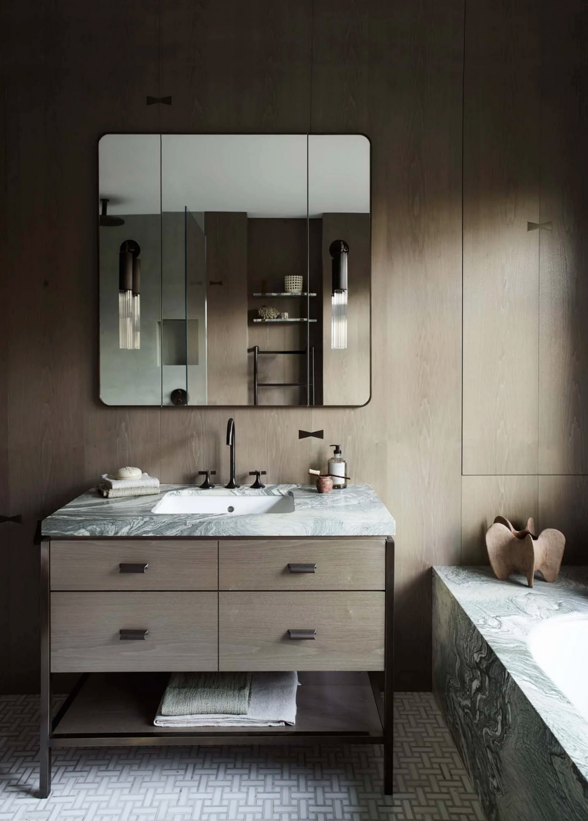 modern bathroom with grey floor tiles, timber wall panelling, gray marble vanity countertop and built-in bath, mirrored medicine cabinet, and timber vanity drawers