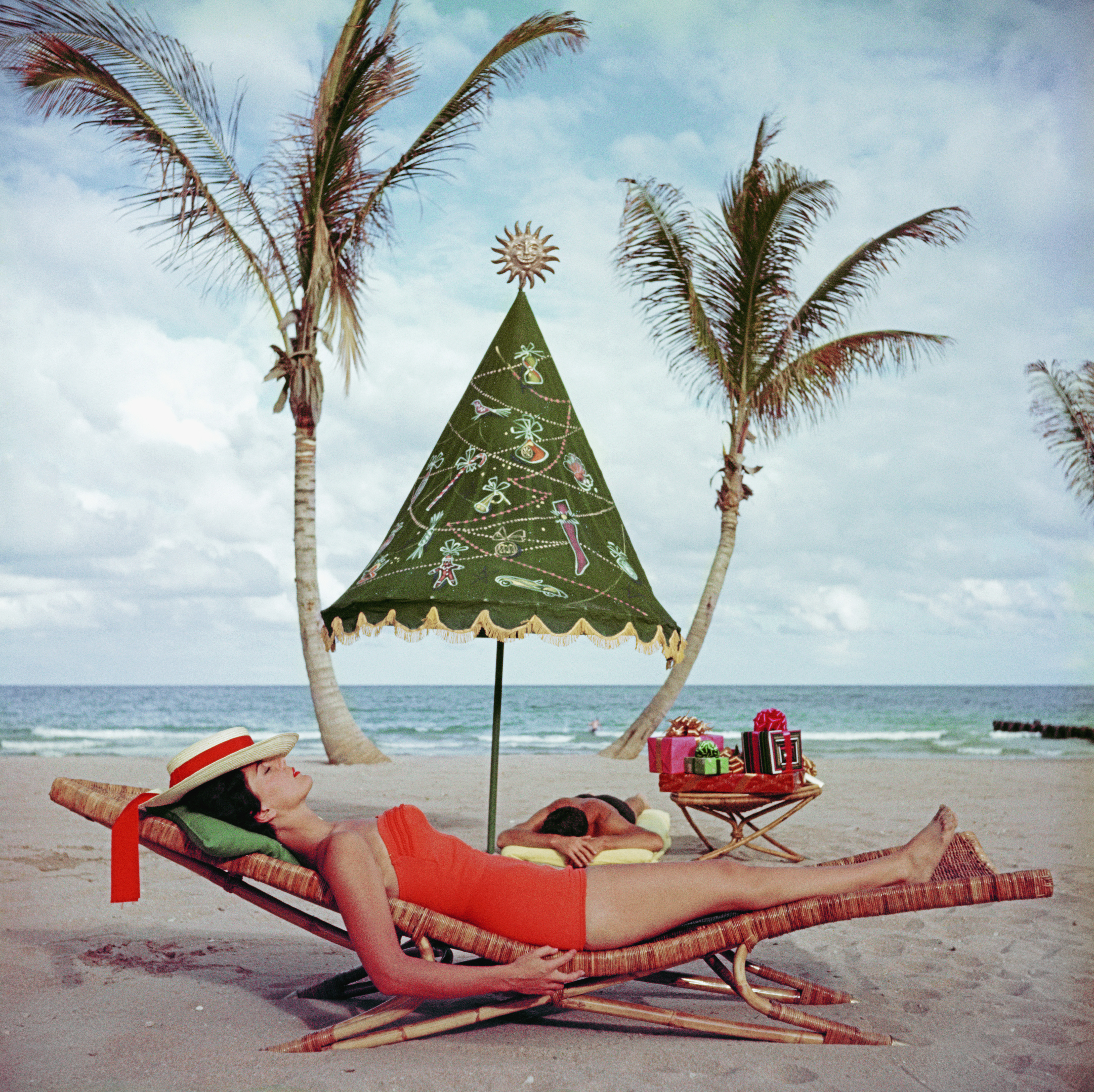 Woman in a coral red swimsuit reclining on a wicker sun lounger
