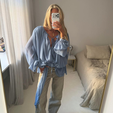 An image of a woman wearing a blouse and jeans summer outfit 2026