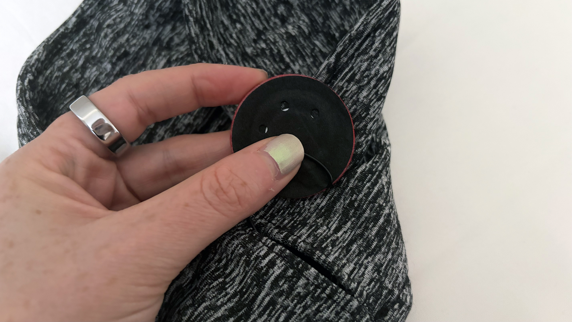 A close up of a hand holding the Snoozeband headphone speaker