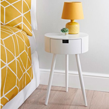 bedroom with white bedside table with yellow lamp