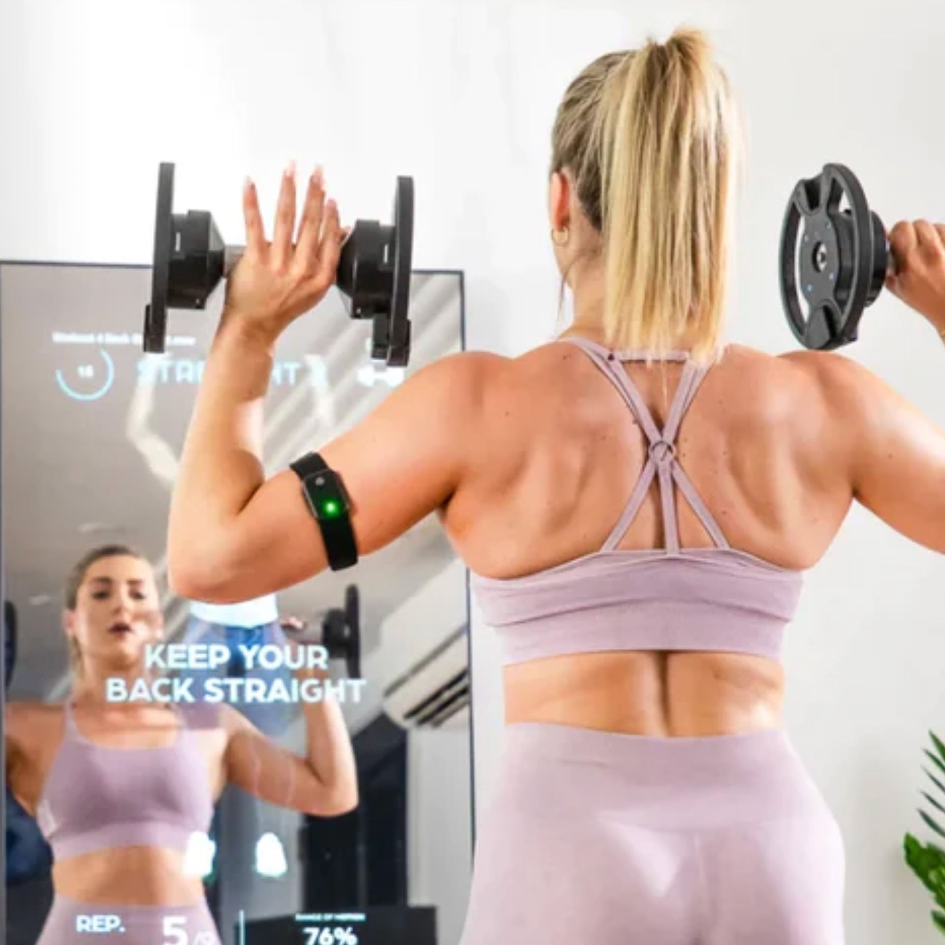 Woman holding weights standing in front of a smart exercise mirror