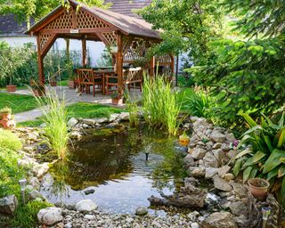 pond in backyard with wooden gazebo