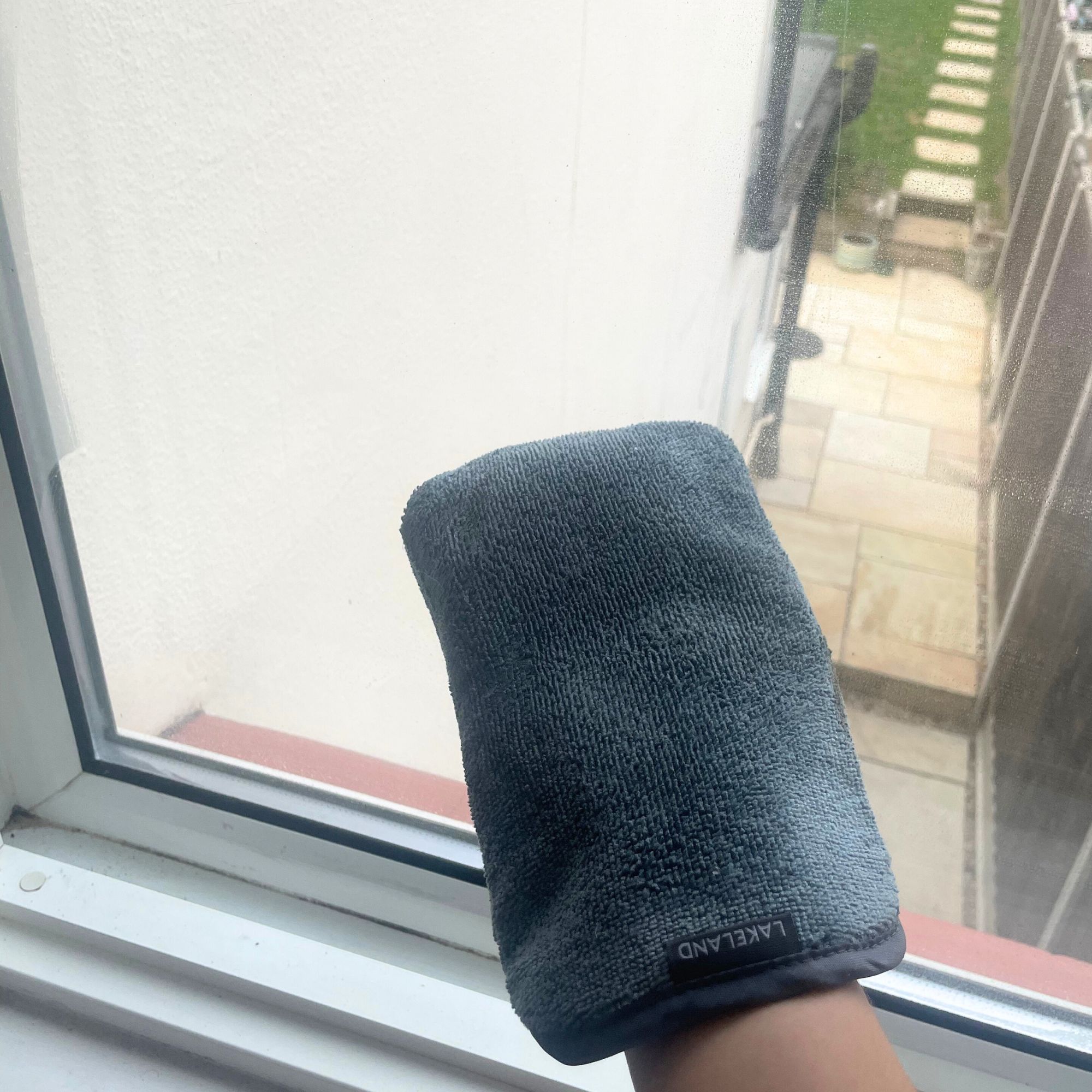 Lakeland condensation mitt on a hand in front of a window looking out to a garden
