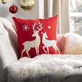 red reindeer Christmas cushion on a cream sofa with hanging ornaments