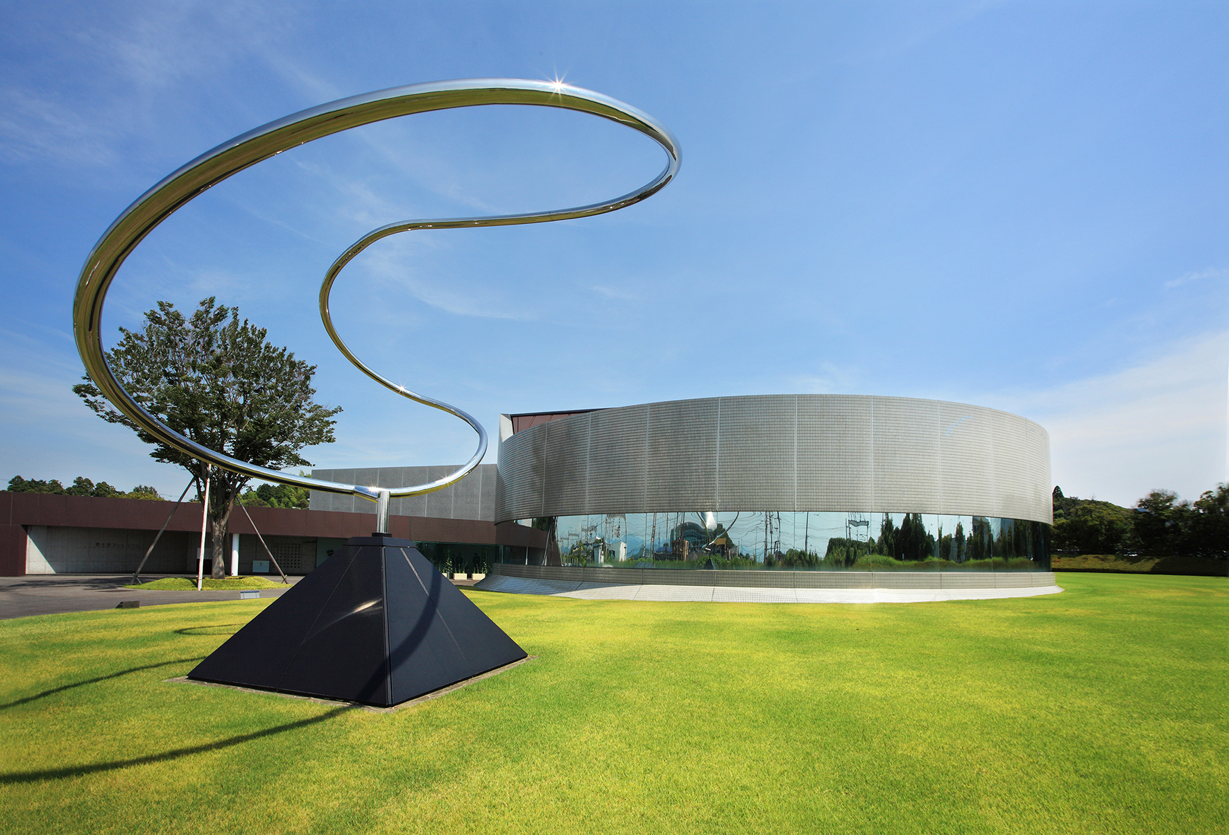 Curving metal sculpture and curved grey and glass building, Shiseido Art House