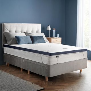 A mattress topper on top of a mattress in a navy blue bedroom