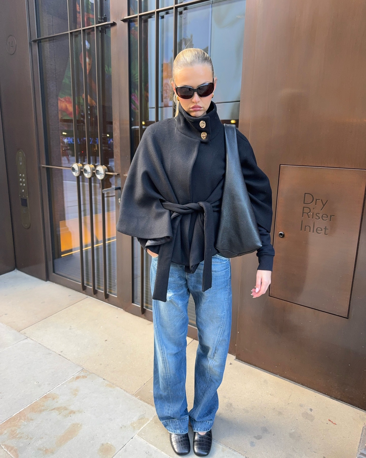 Fashion person @miaisobellebarker wears a London spring capsule wardrobe piece. She wears a funnel-neck cape coat.