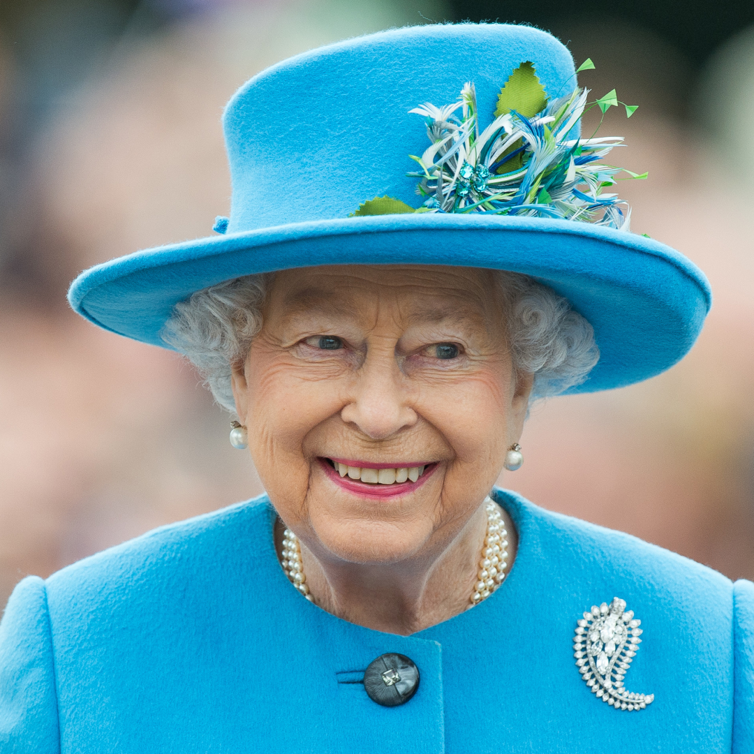 Queen Elizabeth smiling in a blue hat and coat