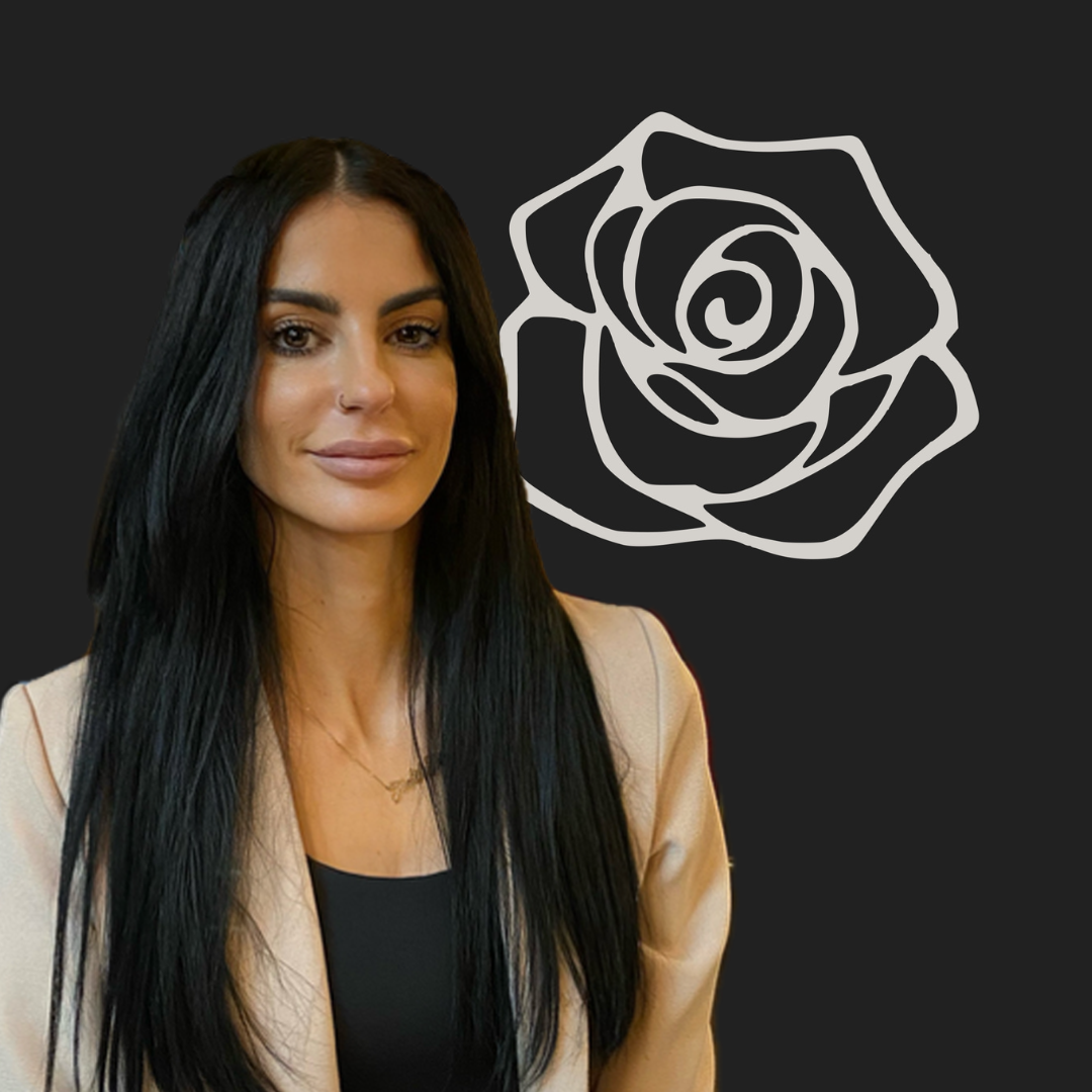 woman with dark hair in front of a picture of a rose