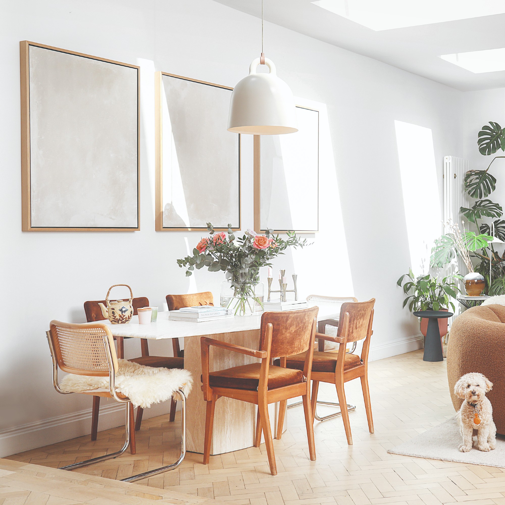 An open-plan dining area with a travertine dining table and mixed dining chairs