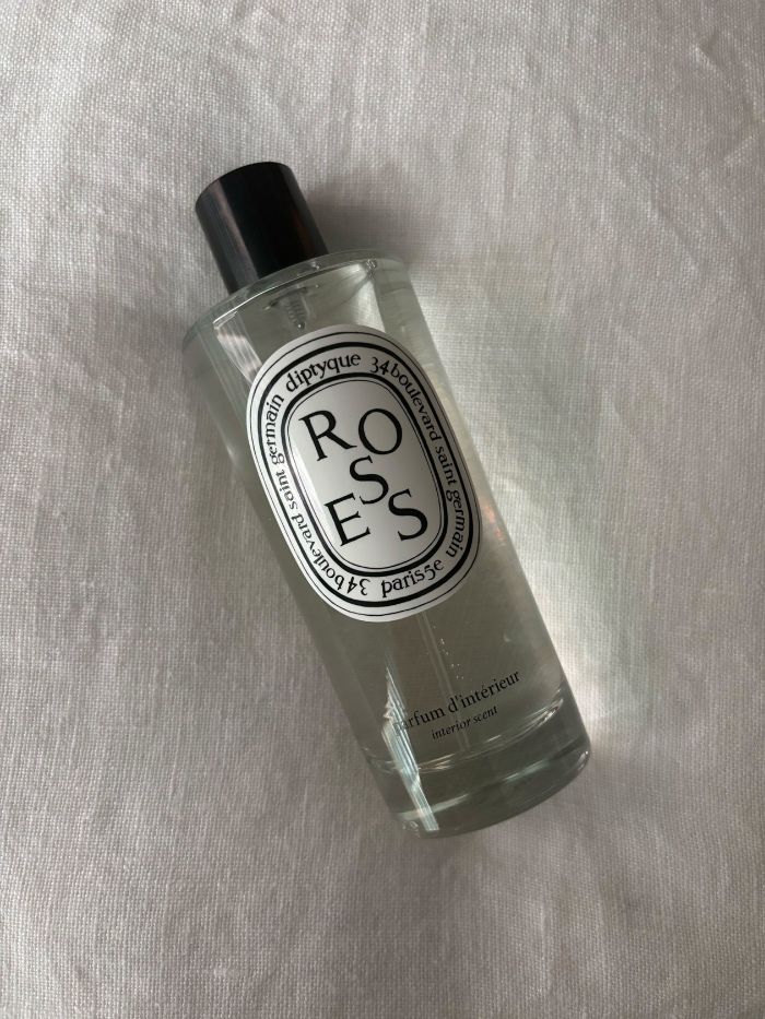 A Diptyque room spray on a white linen background