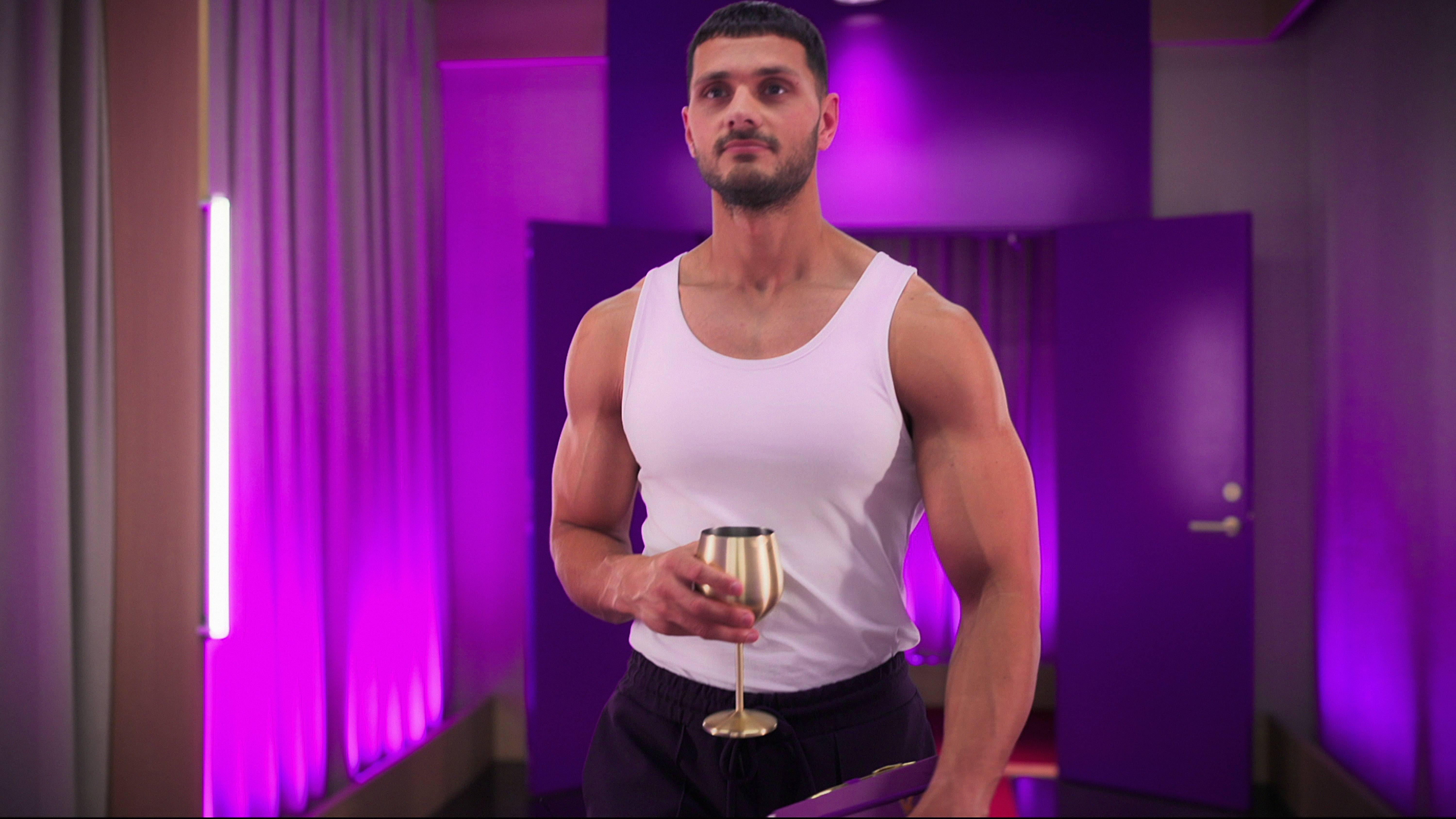 kal wears a white tank top and holds a gold wine glass while in the pods in love is blind uk season 2