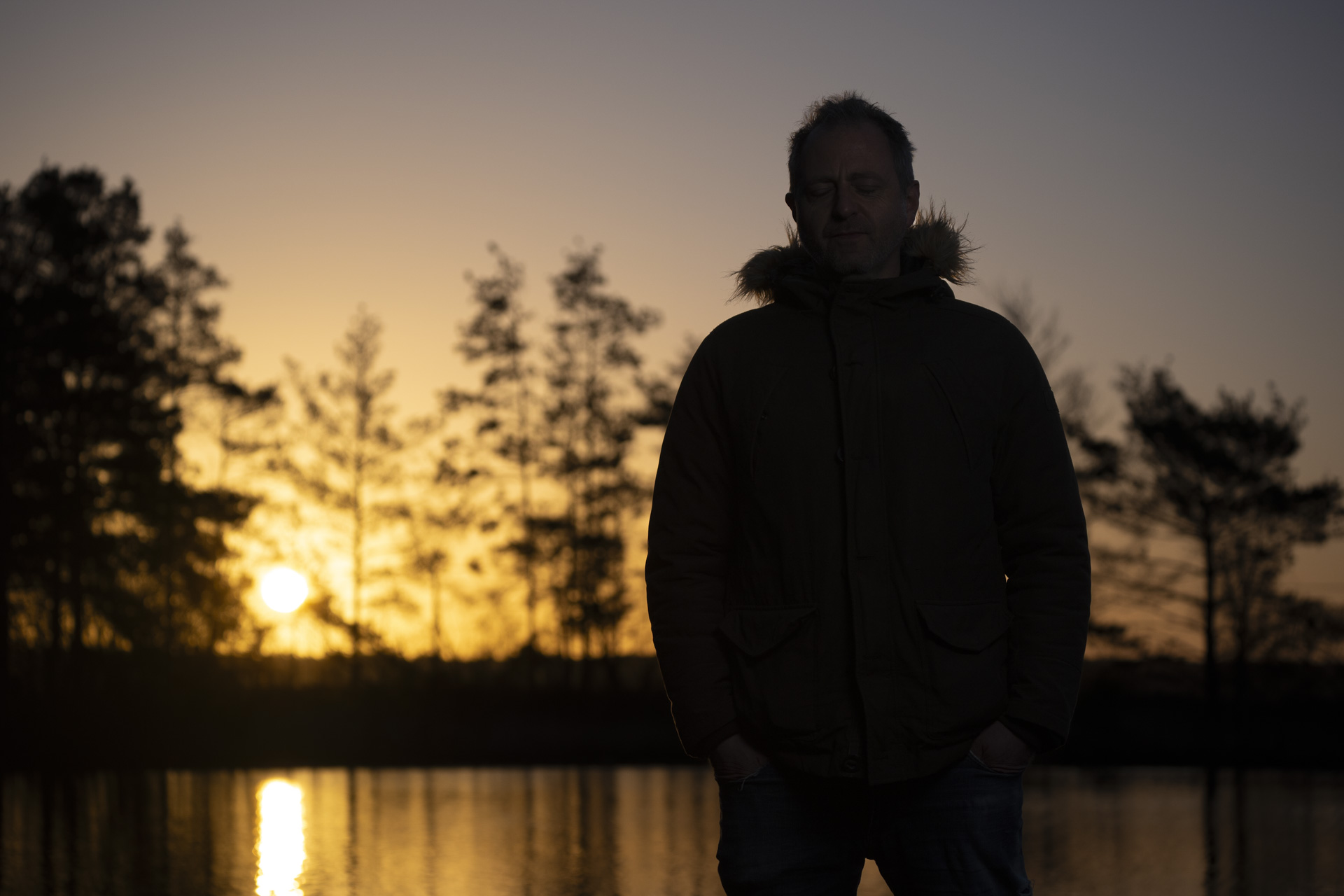 Flash photography portrait taken with the Sony A9 III at first light with golden hour background reflected in a lake