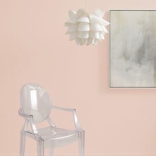 A pink room with a transparent chair and a white light fixture