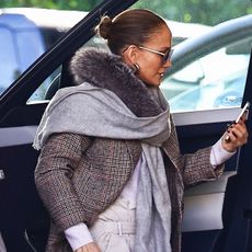 Jennifer Lopez wearing a tweed coat and looking at her phone