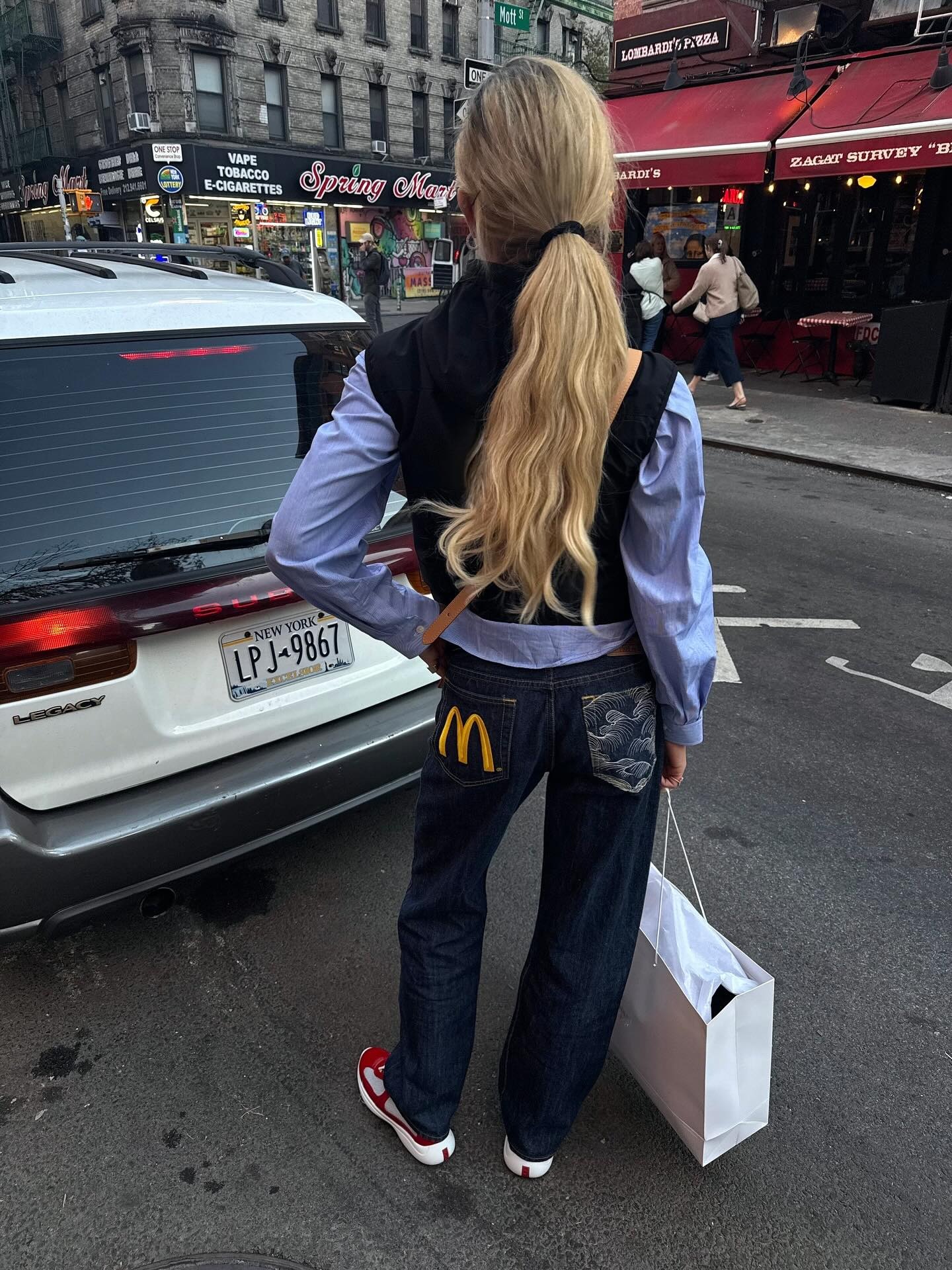 A woman wearing a stylish outfit on a New York street with a low ponytail hairstyle