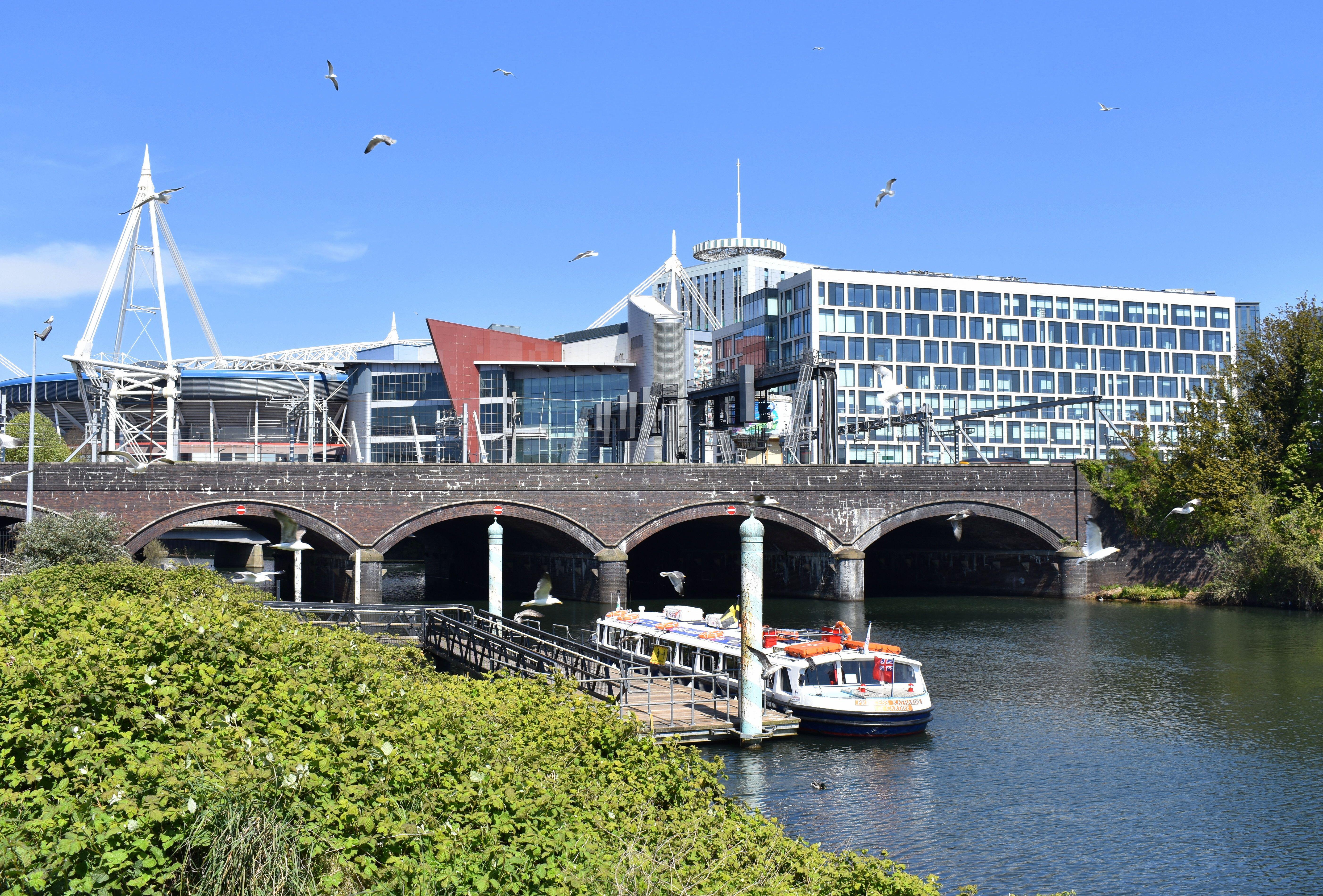 River running under an arched bridge with some modern buildings in the background