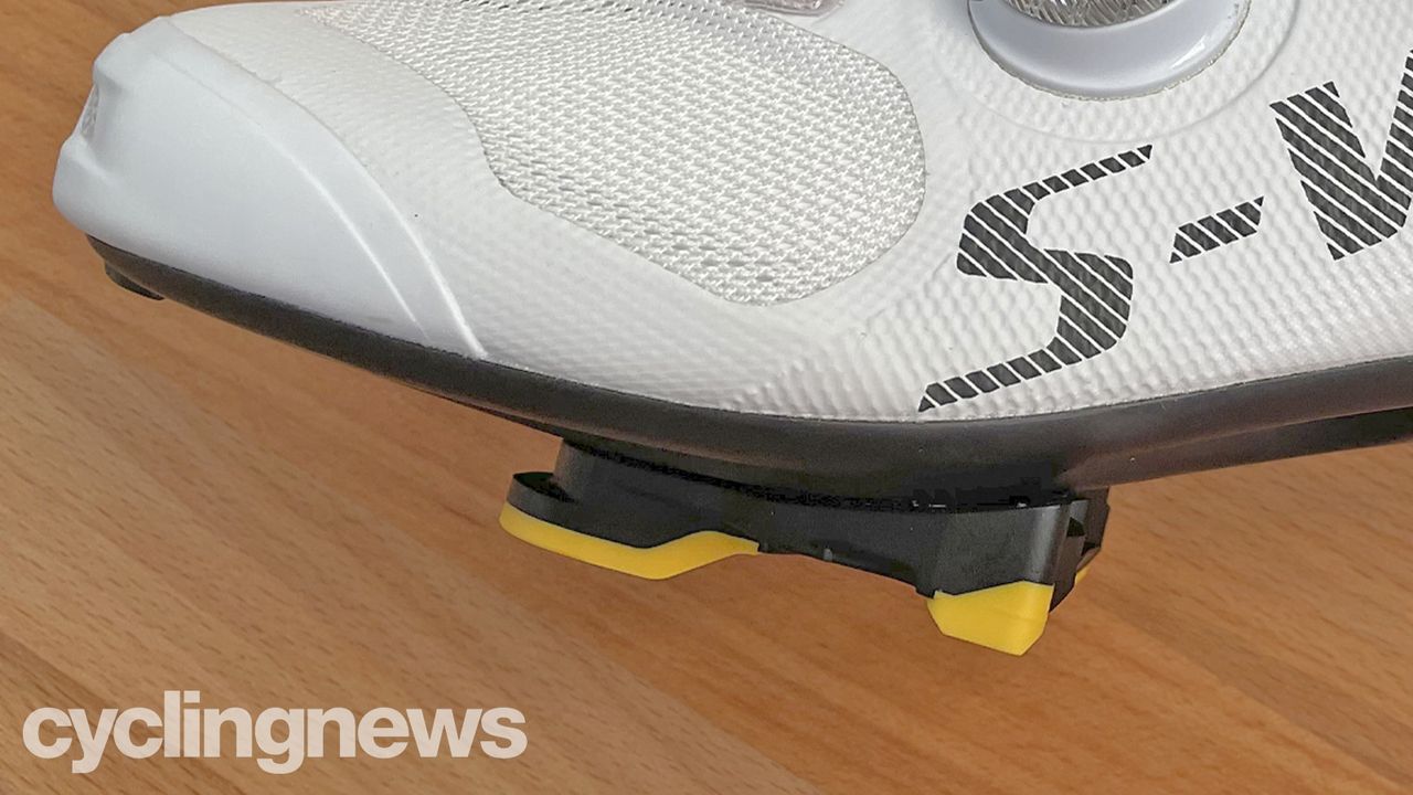 A close up side-on view of the yellow Shimano cleats fitted to a shoe, showing the cleat's height