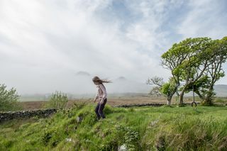 A young girl runs through fields on the Hebrides