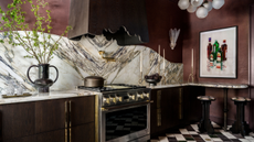 a burgundy red kitchen with a marble backsplash