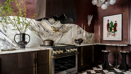 a burgundy red kitchen with a marble backsplash