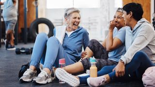 Group of women sitting down and talking,laughing together at the gym