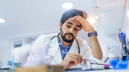 A doctor holds his head in concern.