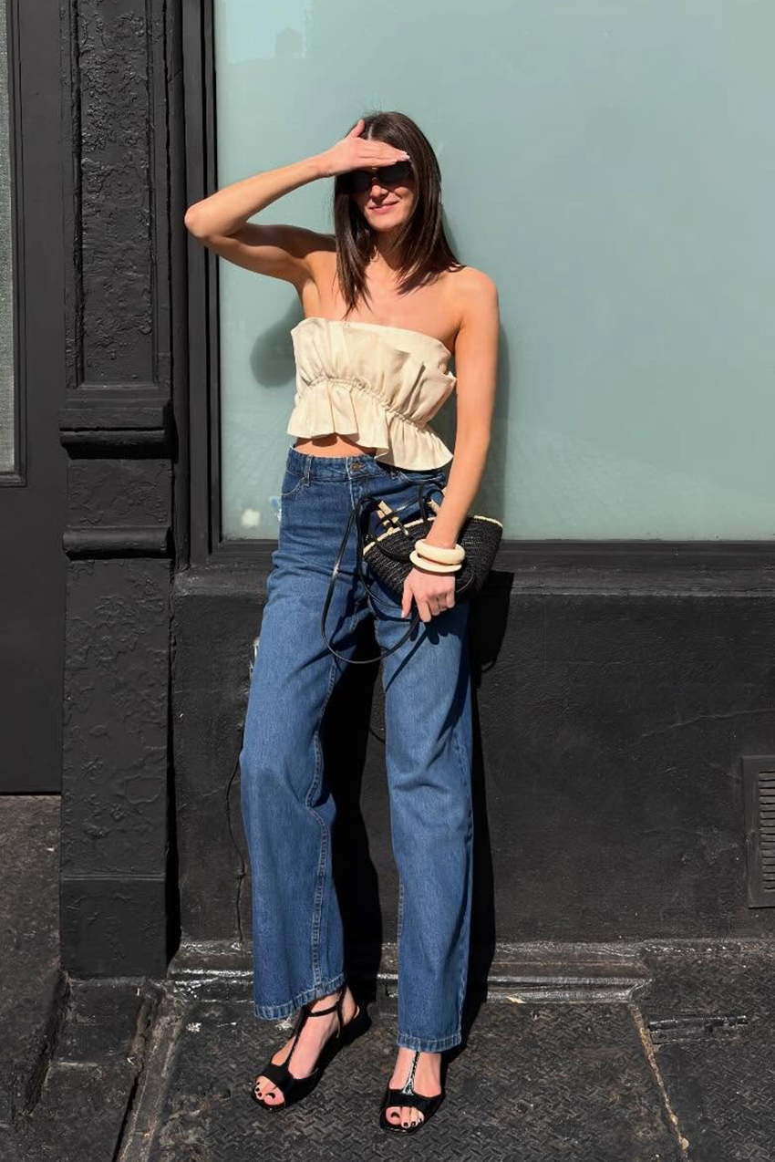 A woman wearing a strapless top with jeans and sandals.