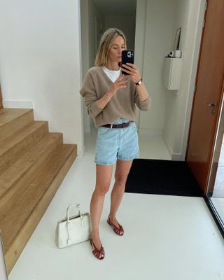 An influencer wearing relaxed denim shorts and a camel sweater