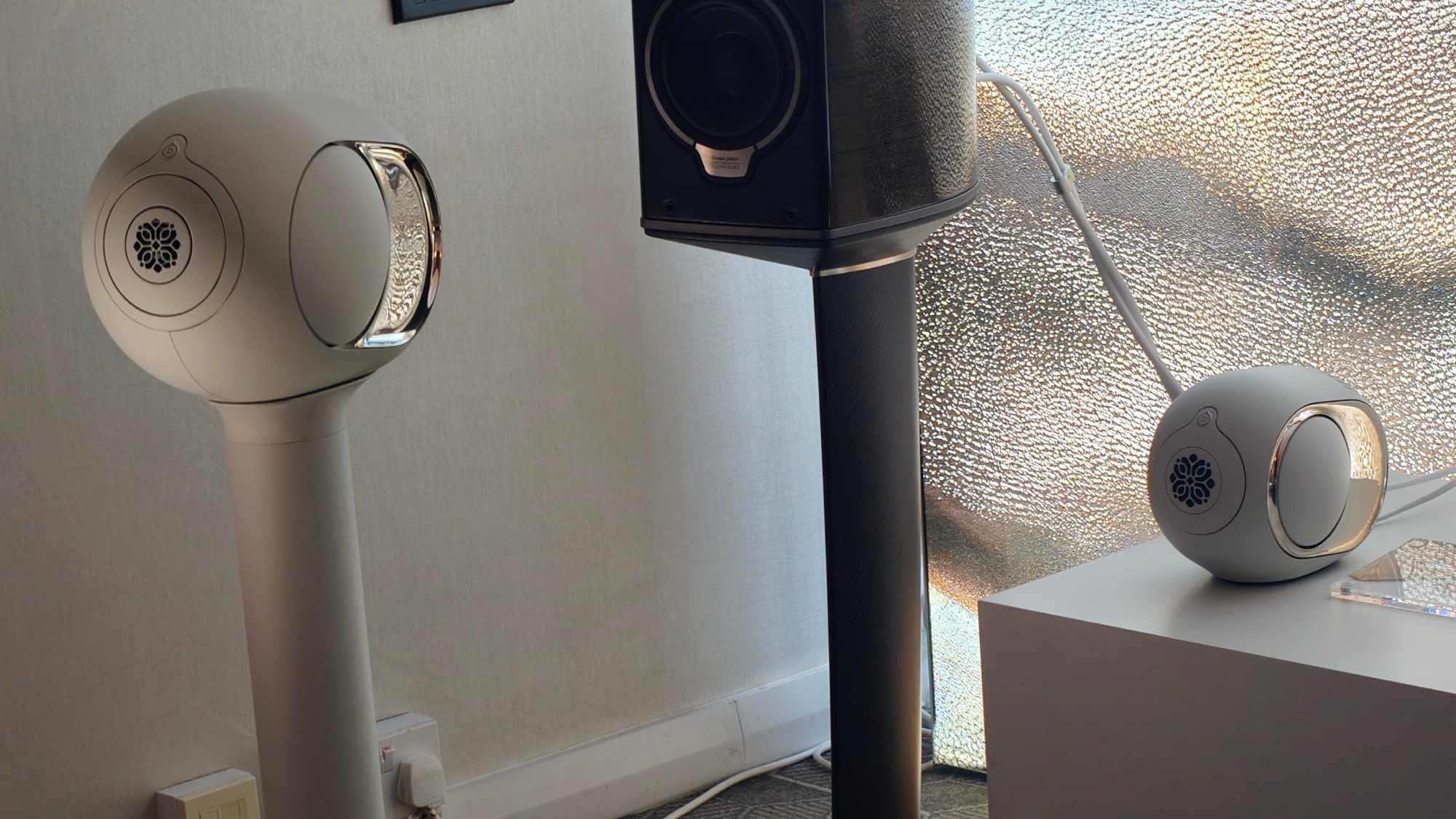 A Devialet Phantom Ultimate 108dB on a stand, next to a Devialet Phantom Ultimate 98dB on a shelf.