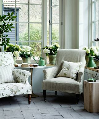 A green and cream colored country living room with floral and striped armchairs.