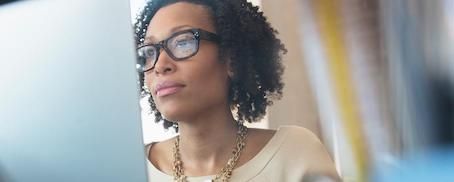 Woman with glasses looking at computer monitor