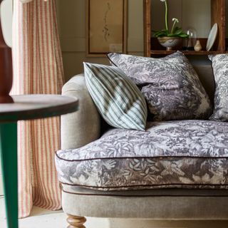 A living room with a two-tone floral-print sofa with contrasting piping and matching cushions