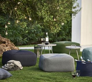 Low lighting ideas for the garden – lighting in the bush, with pouffes and tables surrounding it